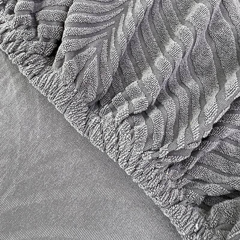 Close-up texture of a gray jacquard stretch sofa cover with a ruffled edge.