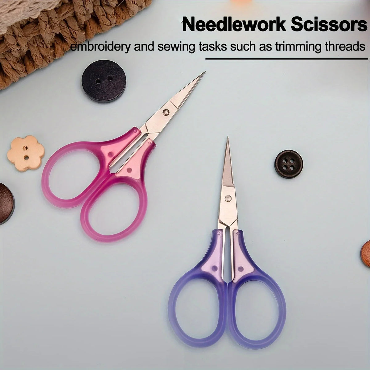 A set of needlework scissors in pink and purple colors with a protective cap shown on a light surface.