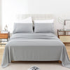 A bed with a gray microfiber flat fitted sheet set and white pillows in a bright bedroom setting.