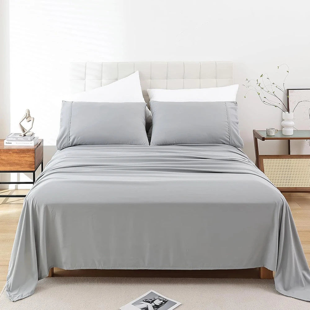 A bed with a gray microfiber flat fitted sheet set and white pillows in a bright bedroom setting.