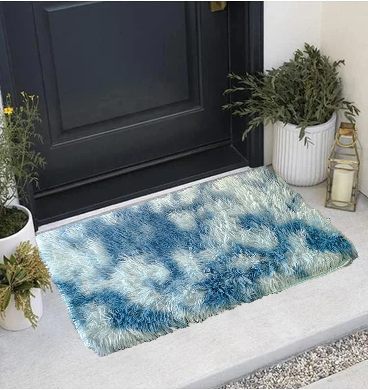 A fluffy blue and white faux fur area rug placed in front of a dark door with potted greenery.
