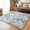 A plush gray long-pile area rug placed on a wooden floor next to a sofa and a window.