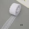 A roll of white floral lace ribbon with a cotton trim for sewing and crafts.