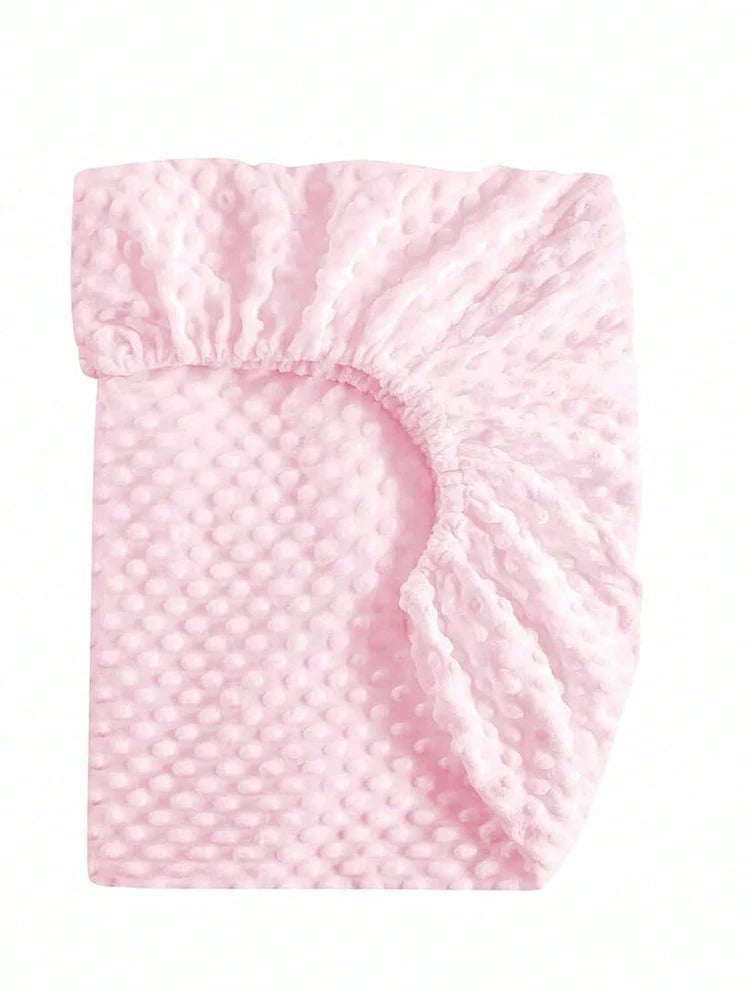 A pink soft plush mattress and diaper changing cover with a textured surface.