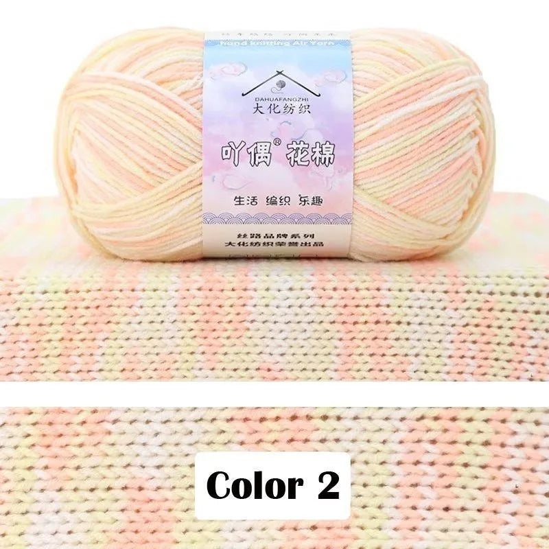 A ball of light pink and cream gradient cotton knit yarn is displayed on a textured fabric background.