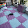 A plush interlocking puzzle rug mat featuring a pink and light blue diamond pattern on a floor.