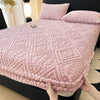 A pink plush jacquard mattress cover with a diamond pattern is shown on a bed.