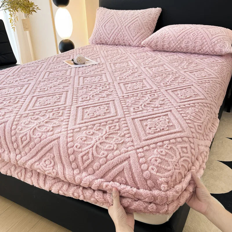 A pink plush jacquard mattress cover with a diamond pattern is shown on a bed.
