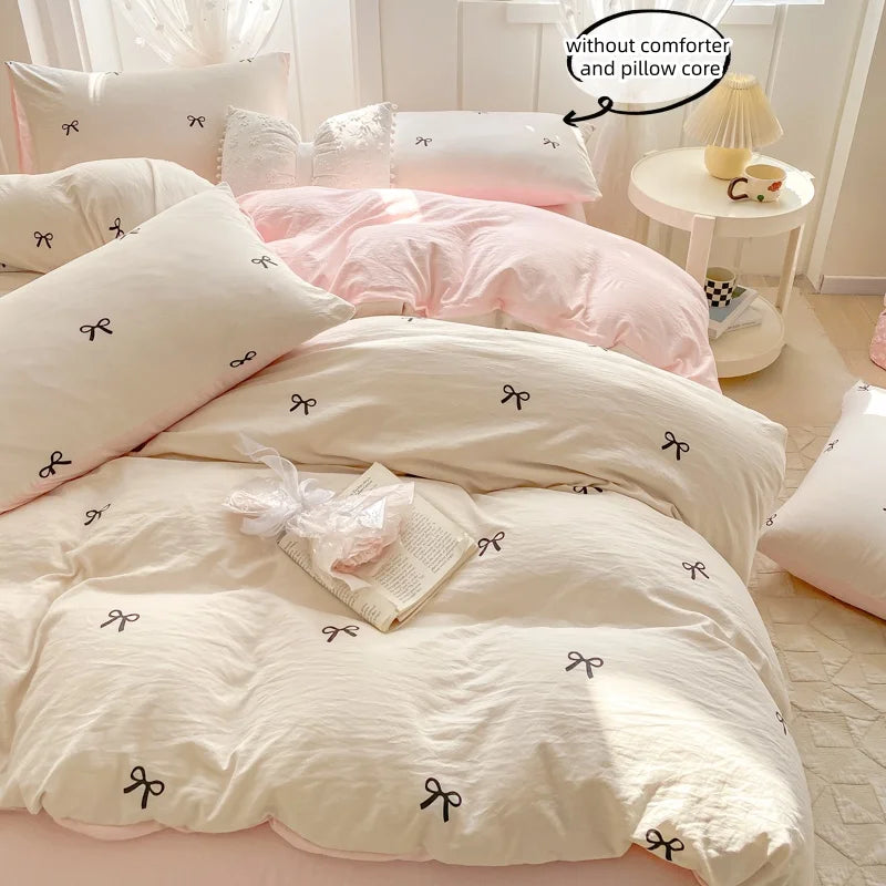 A set of three pink and white bedding pieces including a duvet cover, pillow, and pillow core with bowknot embroidery.