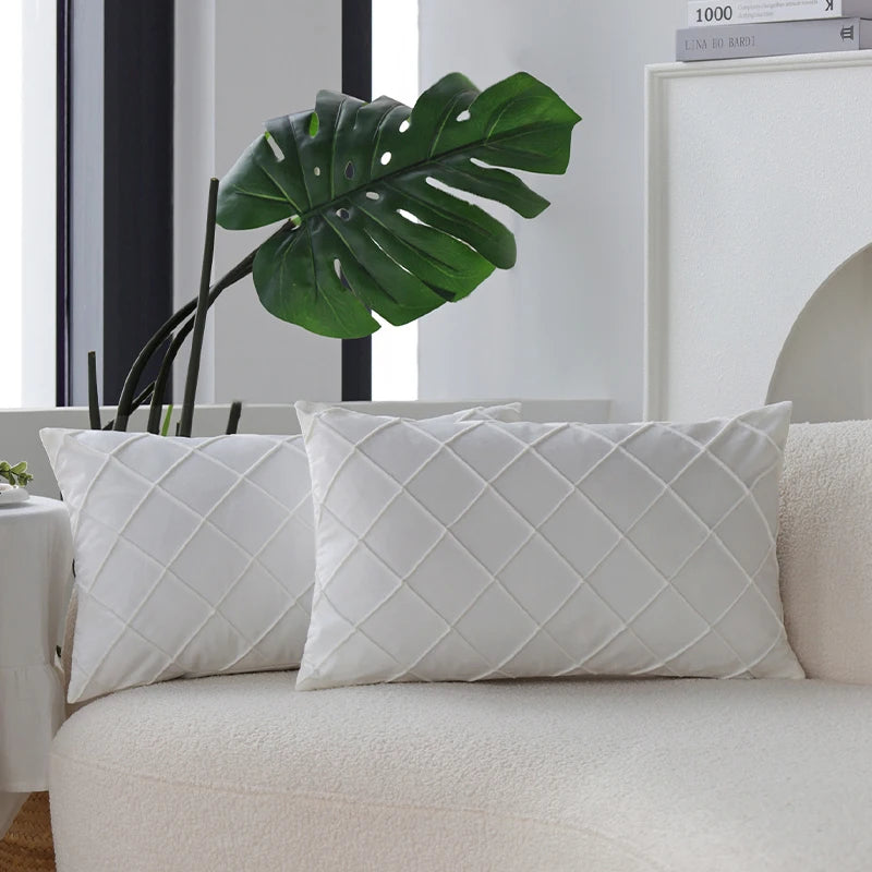 Two white quilted velvet decorative pillow covers resting on a light-colored sofa.