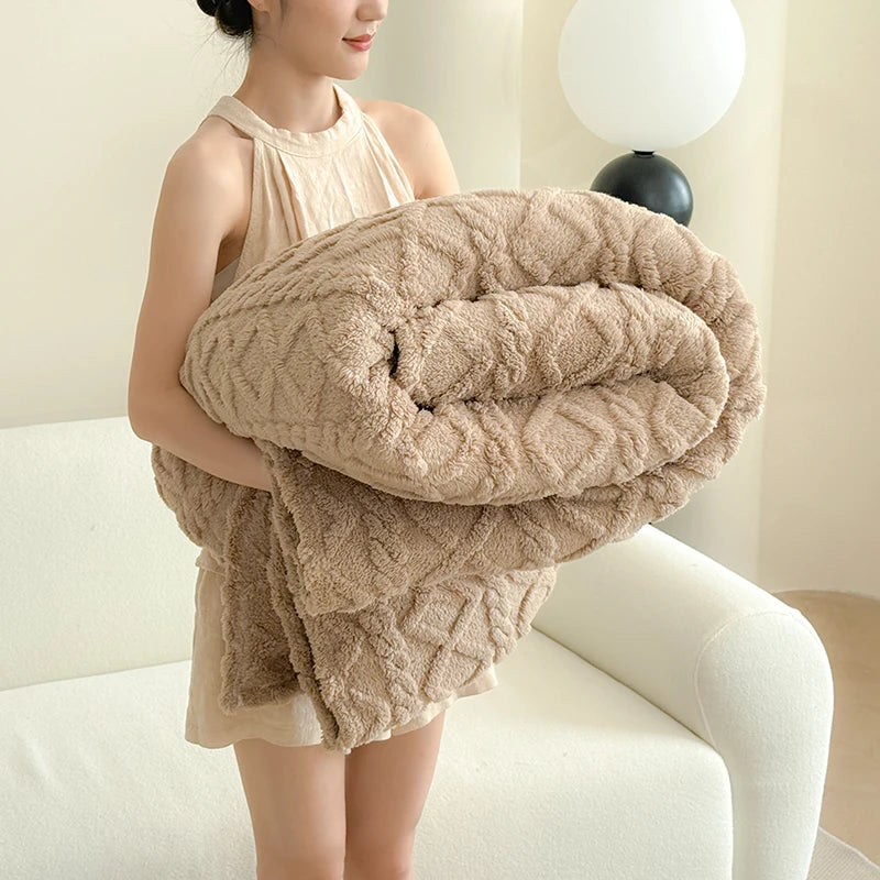 A woman is holding a thick, beige ultra-soft coral fleece blanket in a rolled shape.