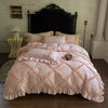 A pink ruffled duvet cover set with three pillows displayed on a bed against a dark headboard.
