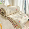 A rolled beige quilt blanket with a pastoral print featuring small animal motifs is displayed on a white surface.