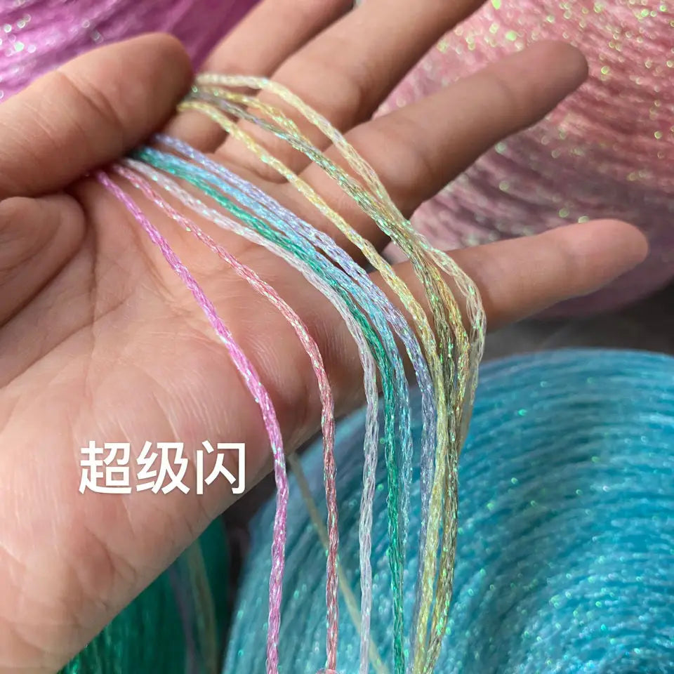 Hand holding multiple strands of glitter metallic yarn in various colors like pink, green, and gold.