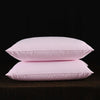 Two pink natural goose down and feather sleeping pillows resting on a dark surface.