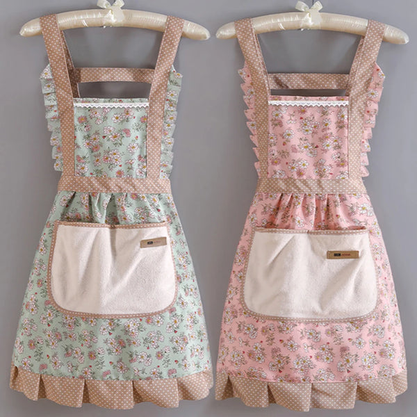 A pink and green floral pattern kitchen apron with adjustable straps displayed on a hanger.