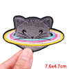 A gray embroidered cat patch with a colorful rainbow border being held by a hand.