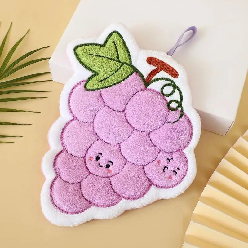 A handmade coral fleece hanging hand towel shaped like a purple strawberry with green leaves.