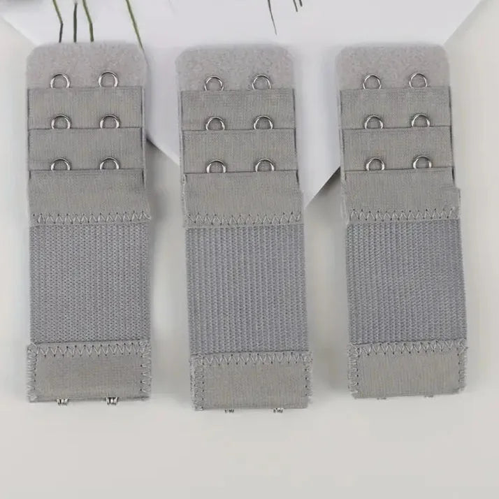 Three gray adjustable bra extender straps laid out on a white background.