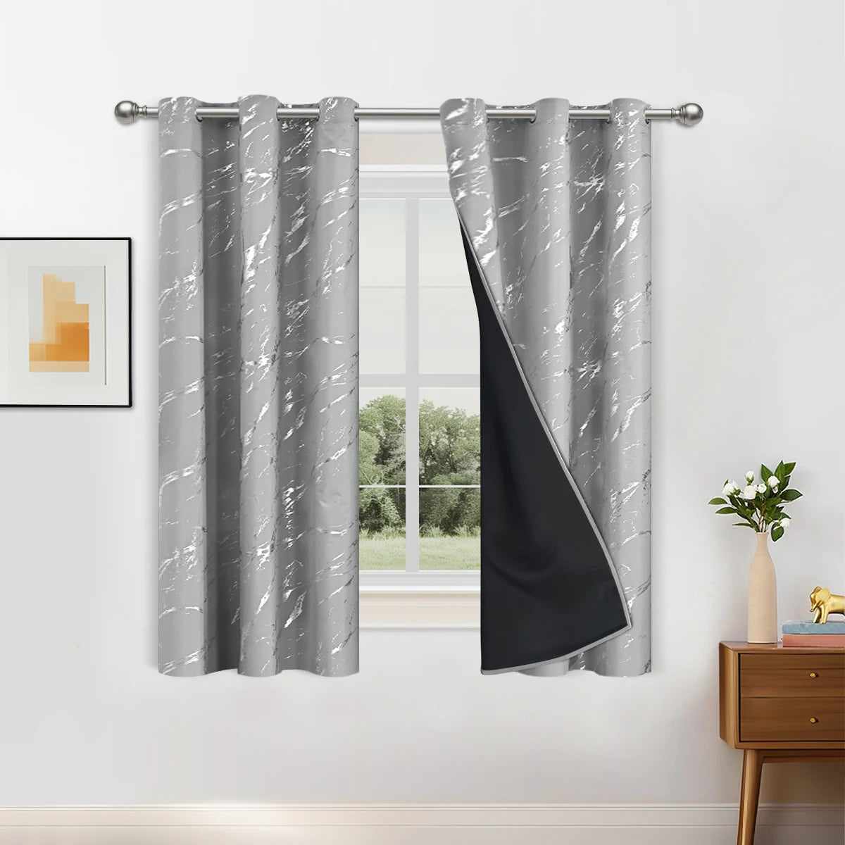 A set of two gray and black blackout curtains with a white marble pattern hanging on a rod.
