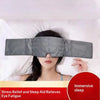 A woman is wearing a gray weighted sleep mask while lying down on white bedding.