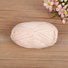 A ball of light pink flat thread yarn for crafting and sewing placed on a wooden surface.