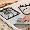 A reusable aluminum stove burner protector mat is shown in a white frame with a black burner grate and a protective silicone 