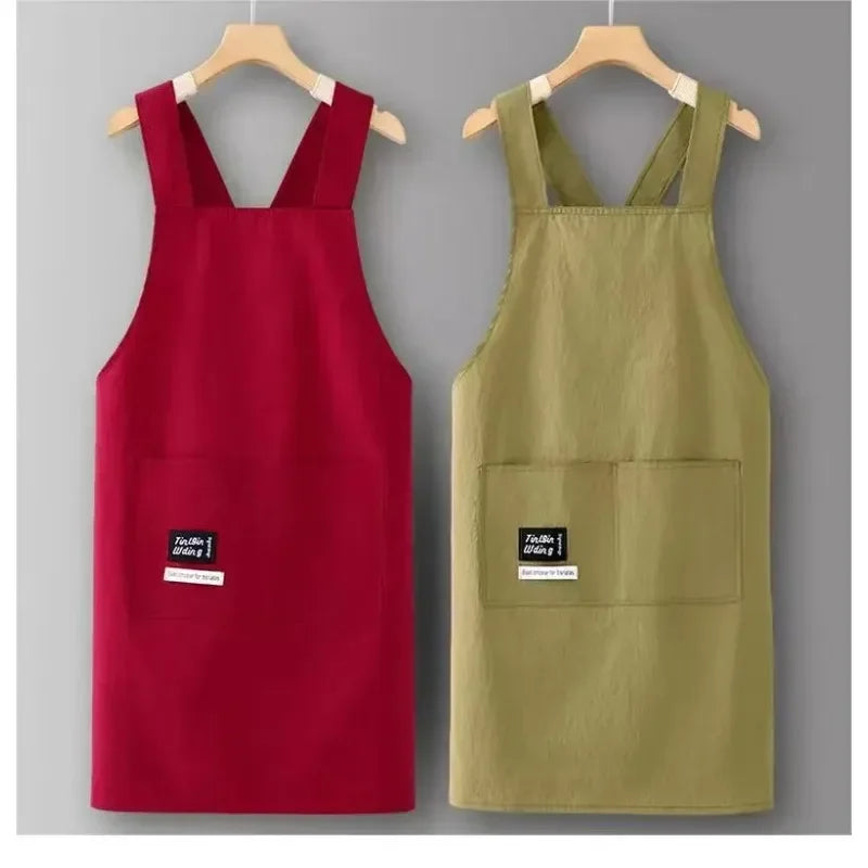 A red water-resistant kitchen apron and a khaki green water-resistant kitchen apron hanging on a hanger.