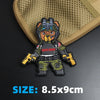 An embroidered bear patch featuring a tactical theme is displayed on a beige fabric background.
