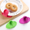 Pink silicone oven mitts with a round cake on a white plate and a green silicone spatula
