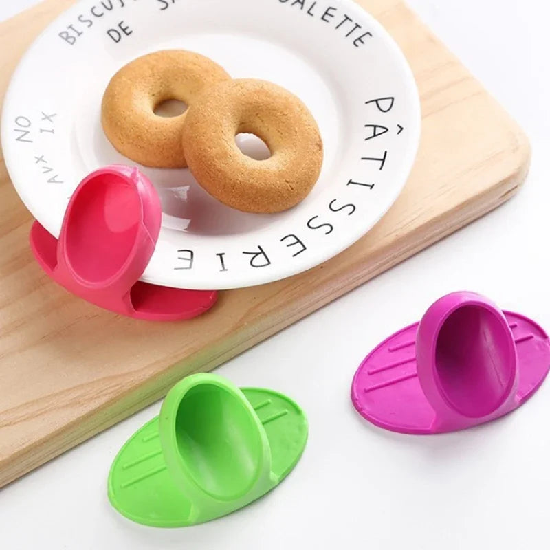 Pink silicone oven mitts with a round cake on a white plate and a green silicone spatula