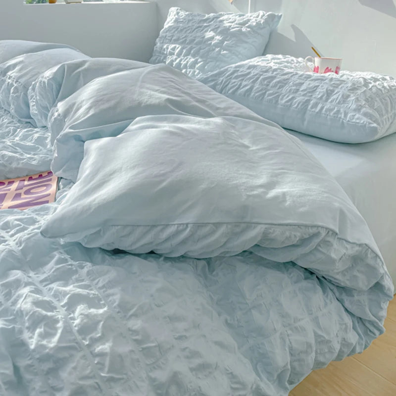 A light blue soft textured duvet cover set with matching pillows on a bed.