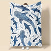 A plush blanket featuring a pattern of blue whale sharks and white dots.