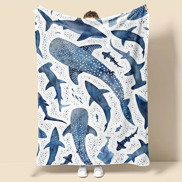A plush blanket featuring a pattern of blue whale sharks and white dots.