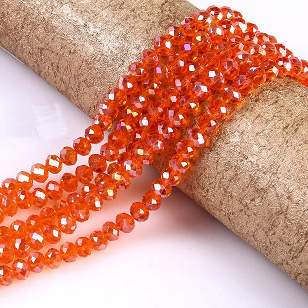 A strand of bright orange faceted rondelle glass beads is shown wrapped around a cylindrical object.