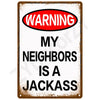 A vintage metal warning sign with a red oval banner that reads WARNING MY NEIGHBORS IS A JACKASS