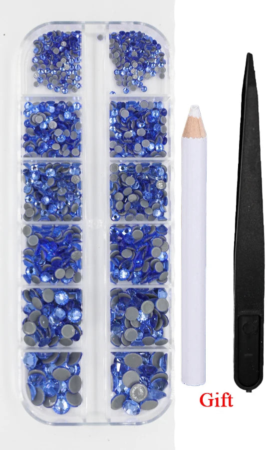 A clear plastic case containing various blue and gray crystal rhinestones and an applicator tool.