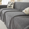 A gray waterproof chenille sofa cover draped over a sofa with a white embroidered pillow.