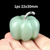 A smooth, light green natural stone pumpkin figurine is held in a hand against a black background.