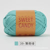 A ball of teal colored hand-dyed fabric strip yarn labeled Sweet Candy