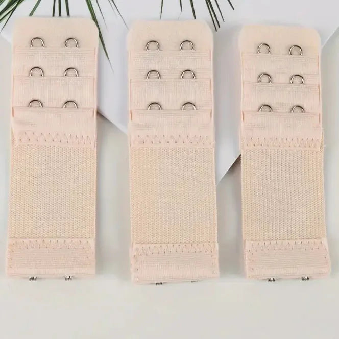 Three beige adjustable bra extender straps with small metal loops and a knitted fabric band.