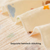 Close-up of a cream colored baby swaddle blanket featuring delicate hemlock stitching and small floral details.