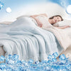 A woman is sleeping comfortably under a white reversible cooling quilt with blue ice cubes scattered on the bedding.