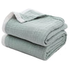A stack of light green breathable 4-layer muslin throw blankets folded neatly.
