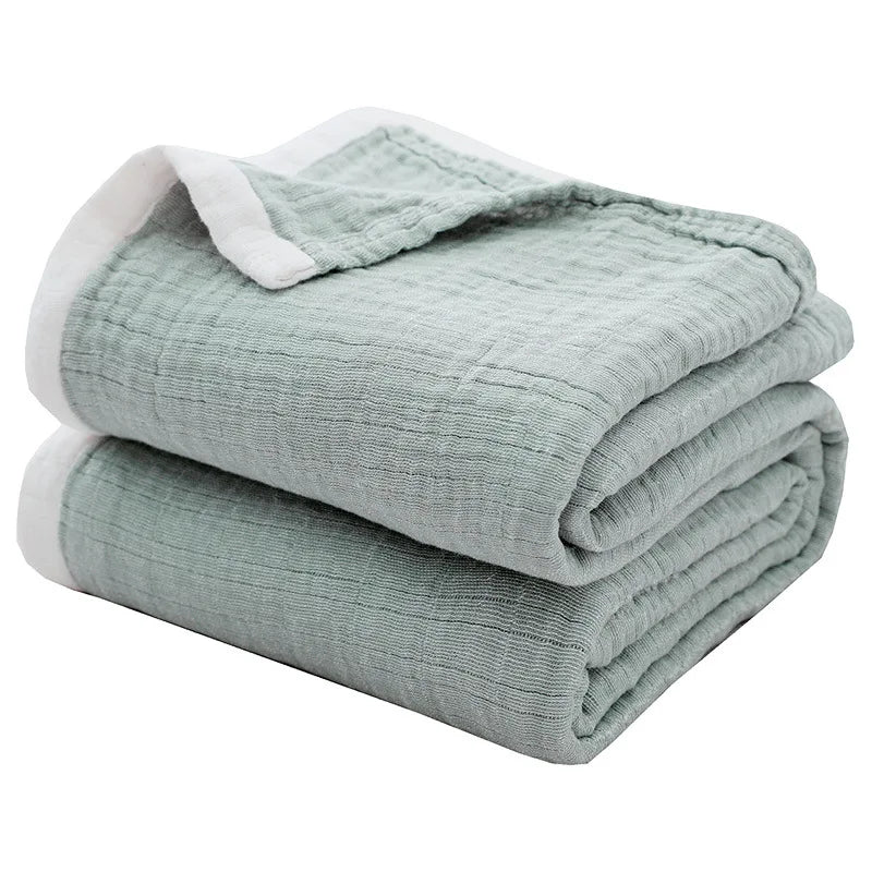 A stack of light green breathable 4-layer muslin throw blankets folded neatly.
