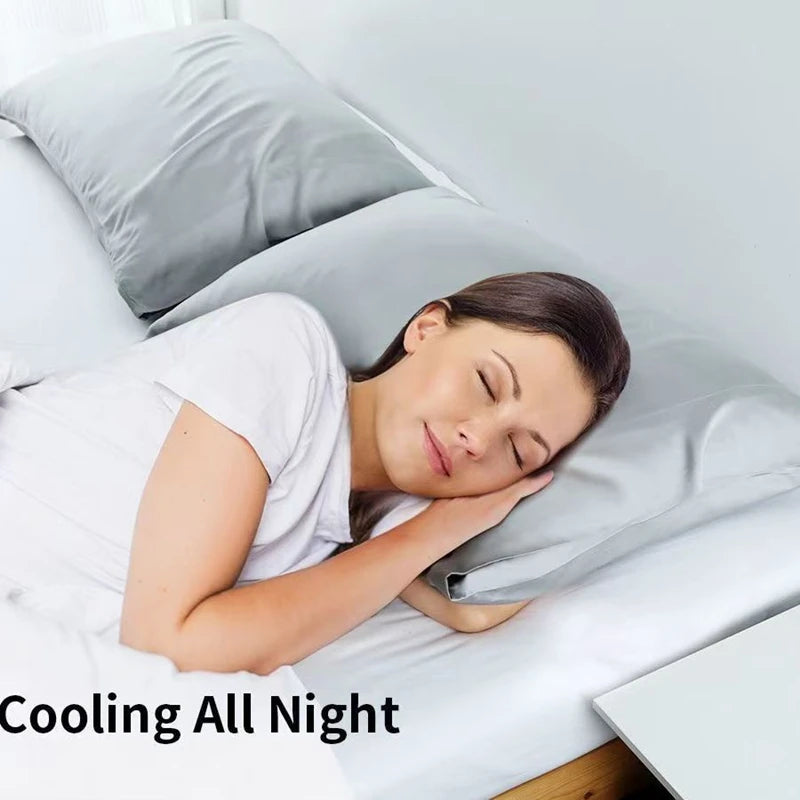 A woman is sleeping comfortably on a white bed with a light gray pillow and sheet, demonstrating cooling comfort.
