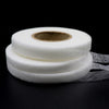 Roll of white double-sided fabric interlining tape on a black background
