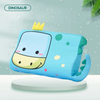 A light blue dinosaur-themed memory foam neck pillow with a yellow crown, resting on a white surface.