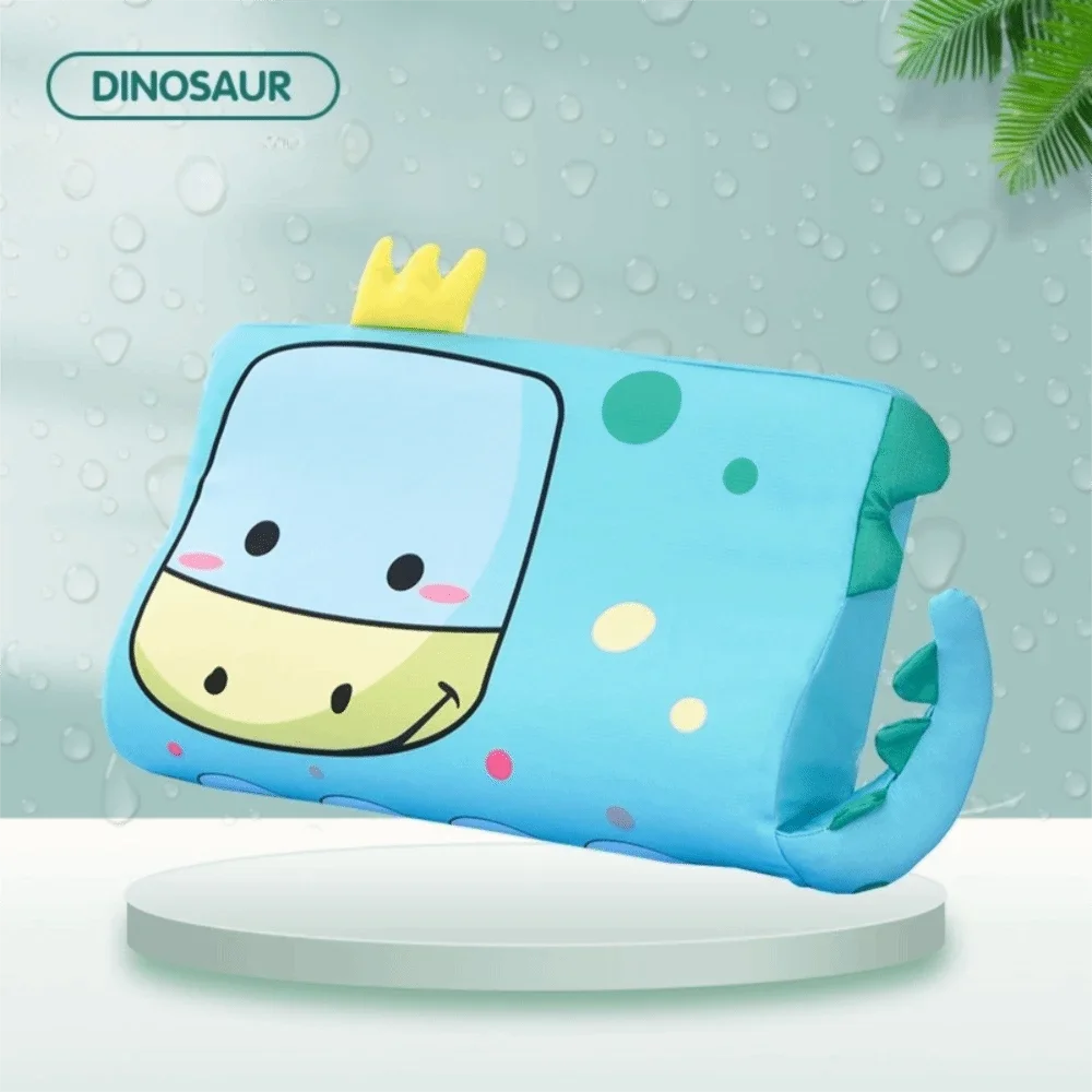 A light blue dinosaur-themed memory foam neck pillow with a yellow crown, resting on a white surface.