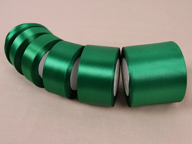 A roll of vibrant green satin ribbon for crafting and decoration, shown in a row.